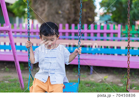 Young Asian boy play a iron swinging at the playground under the sunlight in summer. Young Asian boy play a iron swinging at the playground under the sunlight in summer. 70450836