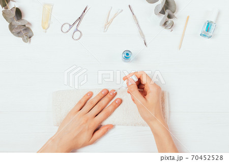Female hands apply nail polish next to self-manicure accessories Female hands apply nail polish next to self-manicure accessories 70452528