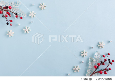 Christmas border made of snowflakes and red berries on blue background Christmas border made of snowflakes and red berries on blue background 70454806