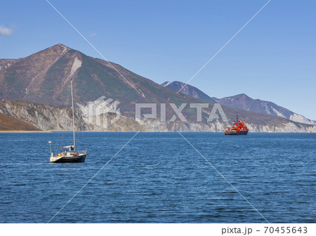 Selective focus. Kamchatka peninsula. Pacific coast. Sailing yacht and red ship in the bay Selective focus. Kamchatka peninsula. Pacific coast. Sailing yacht and red ship in the bay 70455643