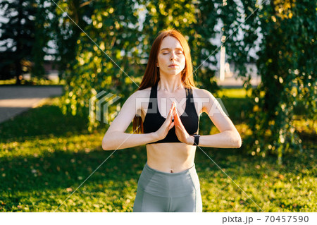 Portrait of attractive meditative young woman with closed eyes performing making hand namaste 70457590