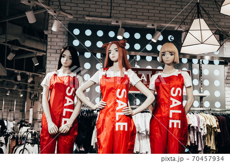 Barnaul, Russia - August 7, 2020. Fashion Mannequins in red overalls and text sale stand in shop window and attract shoppers. Black friday sale in casual store Barnaul, Russia - August 7, 2020. Fashion Mannequins in red overalls and text sale stand in shop window and attract shoppers. Black friday sale in casual store 70457934