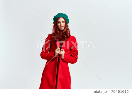 Portrait of a woman in a red coat and in a green hat dark clothes light background model cropped view 70461615