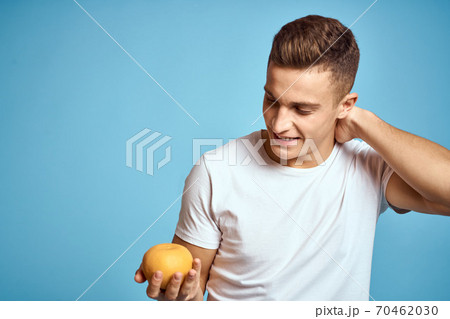 Happy man with fresh fruits gesturing with hands blue background white t-shirt vitamins oranges Happy man with fresh fruits gesturing with hands blue background white t-shirt vitamins oranges 70462030