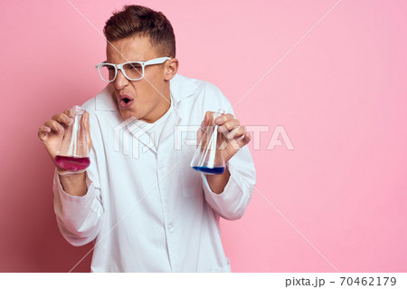 Male laboratory assistant with flasks in the hands of a multicolored liquid chemical substance Male laboratory assistant with flasks in the hands of a multicolored liquid chemical substance 70462179