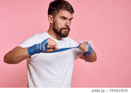 Sporty man in a white T-shirt boxing bandages on the hands of a workout lifestyle pink background 70462850