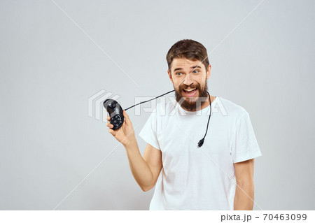 A man with a joystick in his hands fun games lifestyle white t-shirt light background 70463099