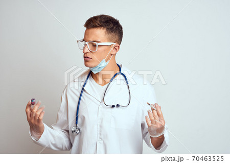 doctor in a medical gown with a stethoscope and glasses on a light background cropped view portrait 70463525
