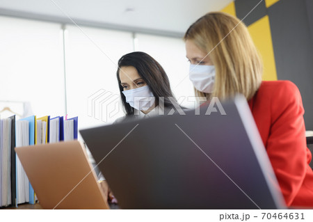 Two business women colleagues are looking at laptop on desktop in office Two business women colleagues are looking at laptop on desktop in office 70464631