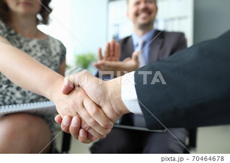 Handshake of man and woman closeup and cheering businessman in background in office 70464678