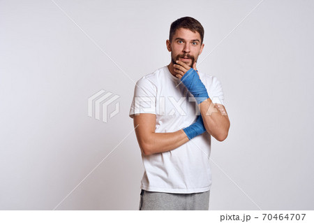 sports man in white t-shirt blue boxing bandages on his arms workout exercises sports man in white t-shirt blue boxing bandages on his arms workout exercises 70464707