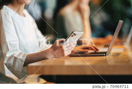 オフィスでスマホを使う女性の手もと 70464711