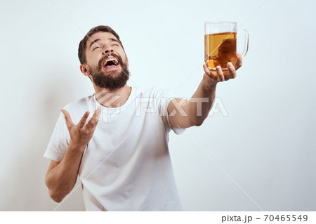 man with a mug of beer in his hands and a white t-shirt light background mustache beard emotions model man with a mug of beer in his hands and a white t-shirt light background mustache beard emotions model 70465549