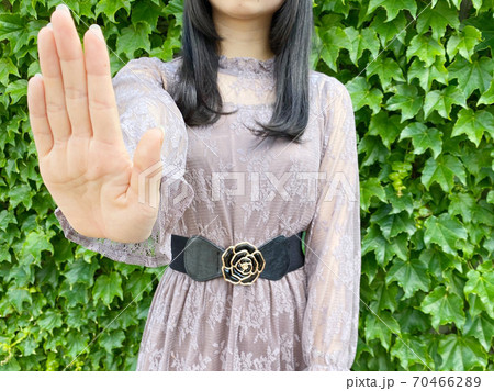 手をかざし拒否する女性 70466289