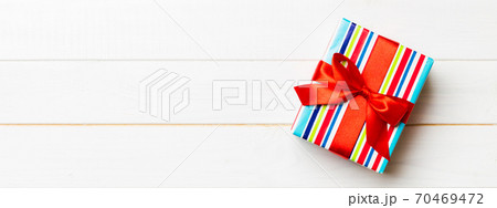 Beautiful gift box with a colored bow on the white wooden table. Top view with copy space for you design. Christmas concept 70469472