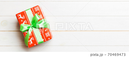 Beautiful gift box with a colored bow on the white wooden table. Top view banner with copy space for you design 70469473