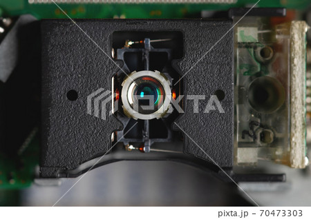 Macro close-up of a DVD drive head with a laser lens on the background of microcircuits. Electronics background Macro close-up of a DVD drive head with a laser lens on the background of microcircuits. Electronics background 70473303