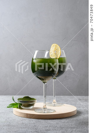 Two chlorella beverage with lemon in glass on gray 70473849