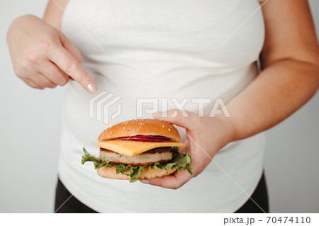 Overweight woman pointing on hamburger Overweight woman pointing on hamburger 70474110