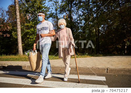 Crossing the street after doing shopping in quarantine 70475217