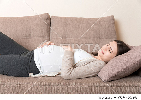 Pregnant woman with painful belly on sofa at home Pregnant woman with painful belly on sofa at home 70476598