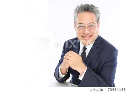 にこやかな笑顔でテーブルに肘を置くビジネスマン 70484183