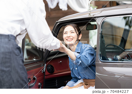 男性のエスコートで車を降りる女性の写真素材