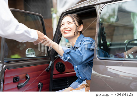 男性のエスコートで車を降りる女性 70484228