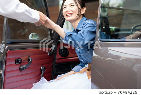 男性のエスコートで車を降りる女性の写真素材