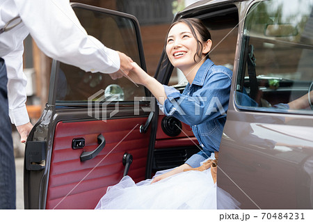 男性のエスコートで車を降りる女性の写真素材
