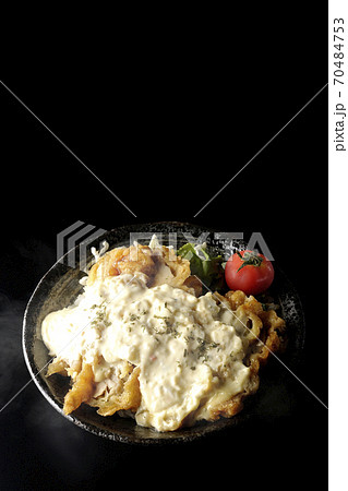ミニトマトなど野菜も一緒に乗っているタルタルソースたっぷりの熱々チキン南蛮丼(黒背景) ミニトマトなど野菜も一緒に乗っているタルタルソースたっぷりの熱々チキン南蛮丼(黒背景) 70484753