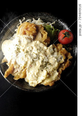 ミニトマトなど野菜も一緒に乗っているタルタルソースたっぷりの熱々チキン南蛮丼(黒背景、俯瞰) ミニトマトなど野菜も一緒に乗っているタルタルソースたっぷりの熱々チキン南蛮丼(黒背景、俯瞰) 70484916