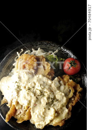 ミニトマトなど野菜も一緒に乗っているタルタルソースたっぷりの熱々チキン南蛮丼(黒背景、俯瞰) ミニトマトなど野菜も一緒に乗っているタルタルソースたっぷりの熱々チキン南蛮丼(黒背景、俯瞰) 70484917