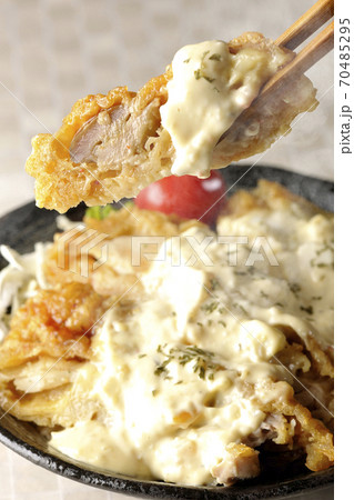 ミニトマトなど野菜も一緒に乗っているタルタルソースたっぷりのチキン南蛮丼の一切れを箸でつまんで食べる ミニトマトなど野菜も一緒に乗っているタルタルソースたっぷりのチキン南蛮丼の一切れを箸でつまんで食べる 70485295