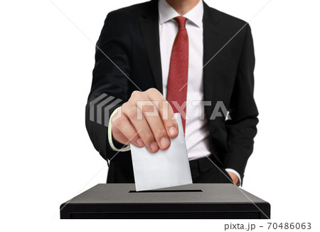 Man casting his vote into ballot box in close up over white background Man casting his vote into ballot box in close up over white background 70486063