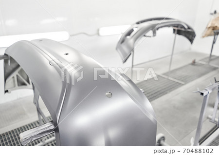 Various parts of the car on the stands for painting. Garage painting car service. Repairing car body work after the accident by working sanding primer before painting. 70488102