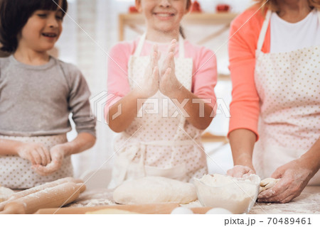 Grandmother teaches grandchildren how to cook. 70489461