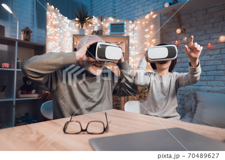 Boy with grandfather look in virtual glasses. Boy with grandfather look in virtual glasses. 70489627