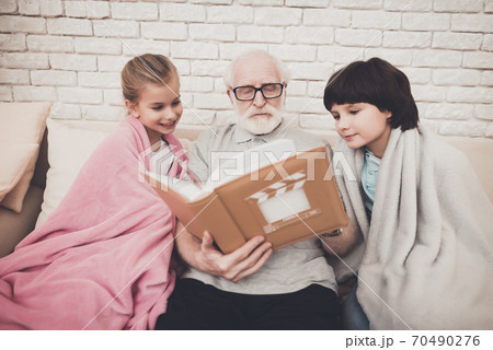 Grandpa and children are watching photos in album. 70490276