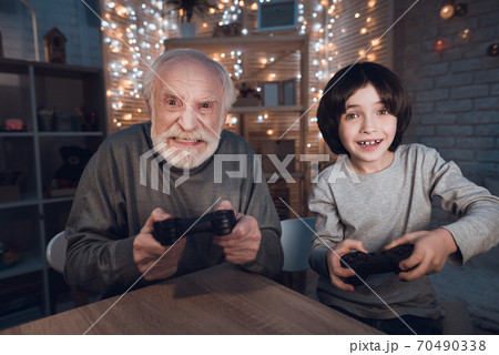 Grandfather and grandson are playing video games. Grandfather and grandson are playing video games. 70490338