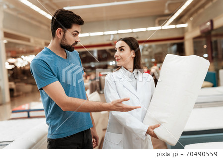 Girl consultant shows a man a pillow. Girl consultant shows a man a pillow. 70490559