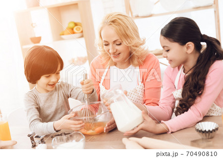 Small smiling boy is whipping eggs in bowl. Small smiling boy is whipping eggs in bowl. 70490810