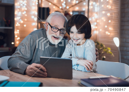 Cheerful grandfather with a grandson sits at table Cheerful grandfather with a grandson sits at table 70490847