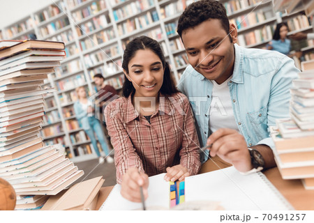 A man sits next to a girl in the library.  70491257
