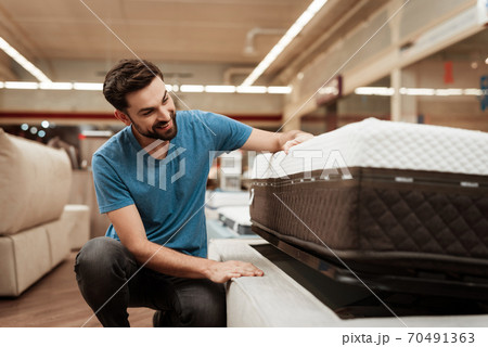 A man in mattress store chooses quality mattress. 70491363