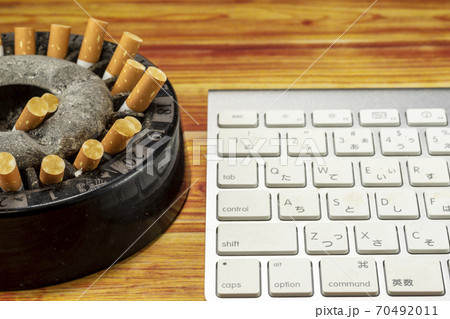 Ashtray full of butts and keyboard - Stock Photo [70492011]