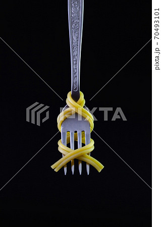 Freshly cooked pasta on a old fork on the black background. 70493101