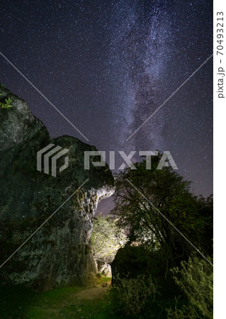 Narrow illuminated space between rocks under milky way 70493213