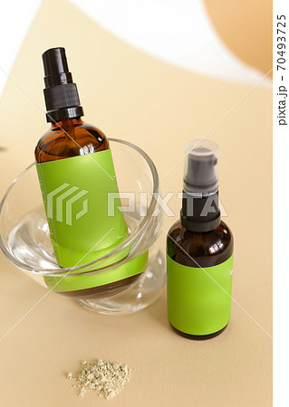 Close up glass spray bottle wirth cosmetic product and green space for brand near leaf. Close up glass spray bottle wirth cosmetic product and green space for brand near leaf. 70493725