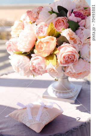 Pink roses in vase near little pillow on table. 70493881